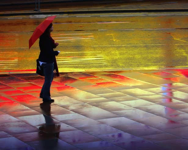 A woman with an umbrella stands in the rain at Liverpool Lime Street. Image: Christopher Furlong/Getty Images