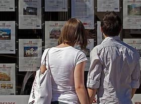 First time buyers looking at houses for sale in an estate agents window. 