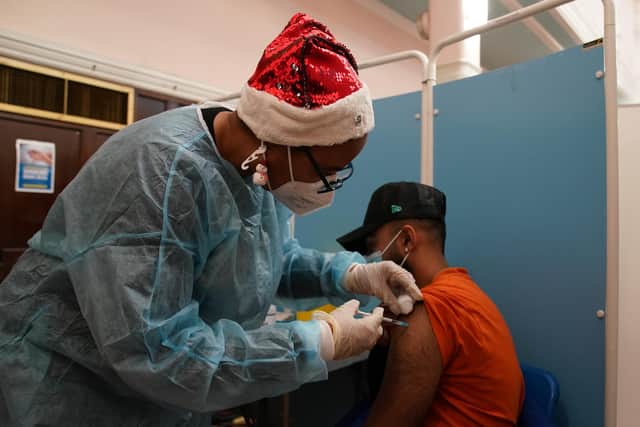 A vaccinator administers a 'Jingle Jab' Covid vaccination booster injection at Redbridge Town Hall, in Ilford, Essex, as the coronavirus booster programme continues across the UK on Christmas day.Picture date: Saturday December 25, 2021.