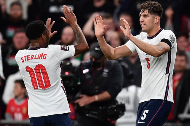 England's defender John Stones (R) celebrates with England's midfielder Raheem Sterling after scoring the equalising goal during the FIFA World Cup 2022 qualifying match between England and Hungary at Wembley Stadium in London on October 12, 2021. (Photo by BEN STANSALL/AFP via Getty Images)